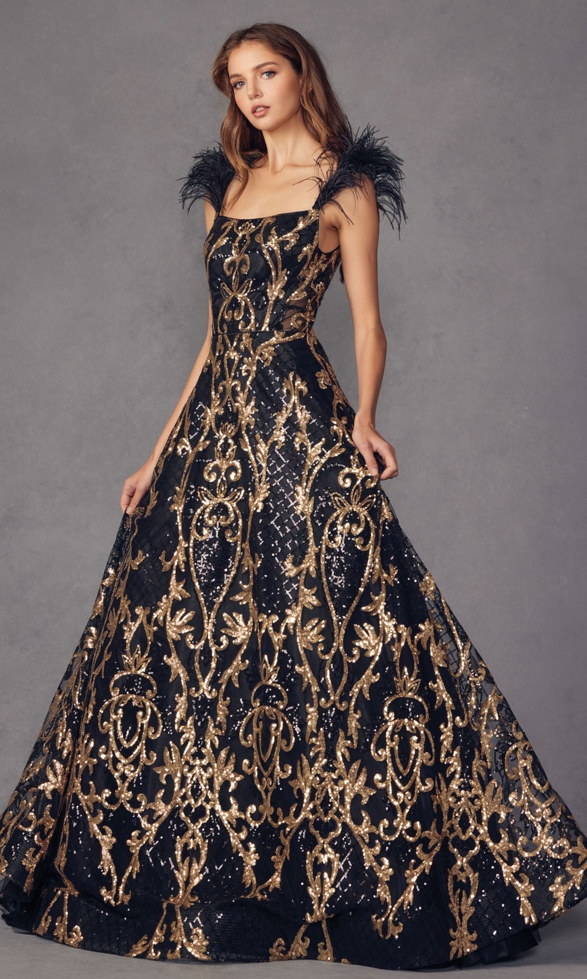 A woman models the Feathered-Cap-Sleeve Long Sequin Prom Ball Gown 297, featuring gold baroque patterns and feathered cap sleeves, against a plain gray background.